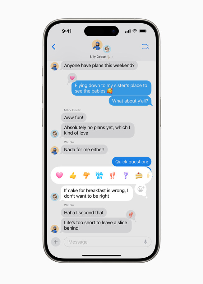 Op een iPhone 15 Pro is een iMessage geselecteerd met verschillende emoji voor tapbacks, waaronder een hartje, duim omlaag, duim omhoog, ‘haha’, uitroepteken, vraagteken en een taart.