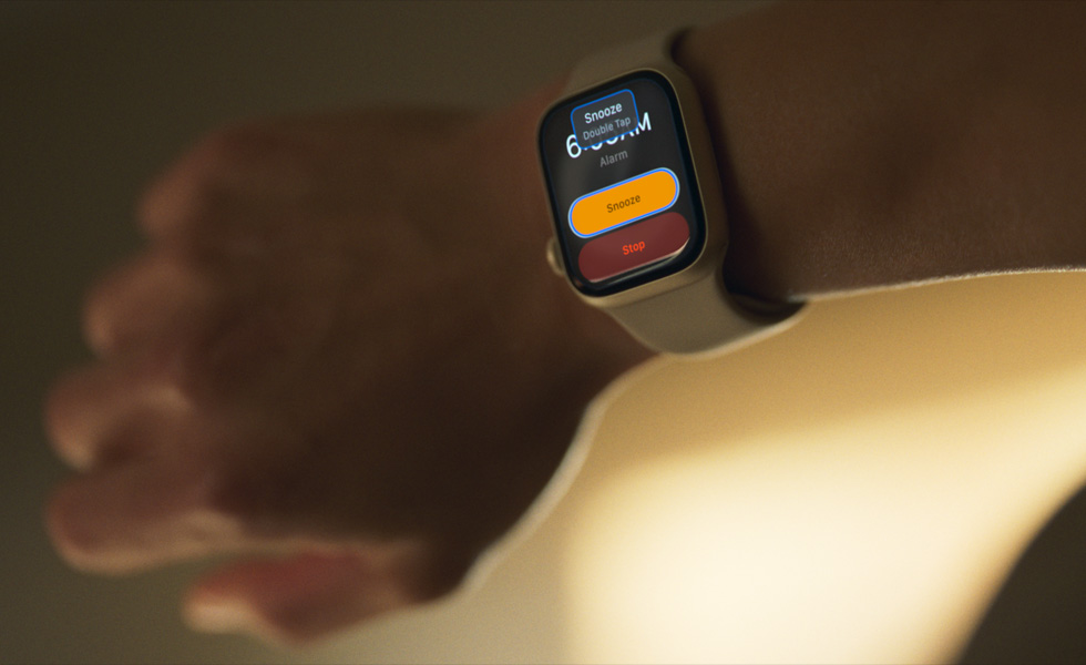 แขนข้างหนึ่งที่มี Apple Watch ซึ่งบอกว่า "เลื่อนปลุก แตะสองครั้ง" บนหน้าจอ