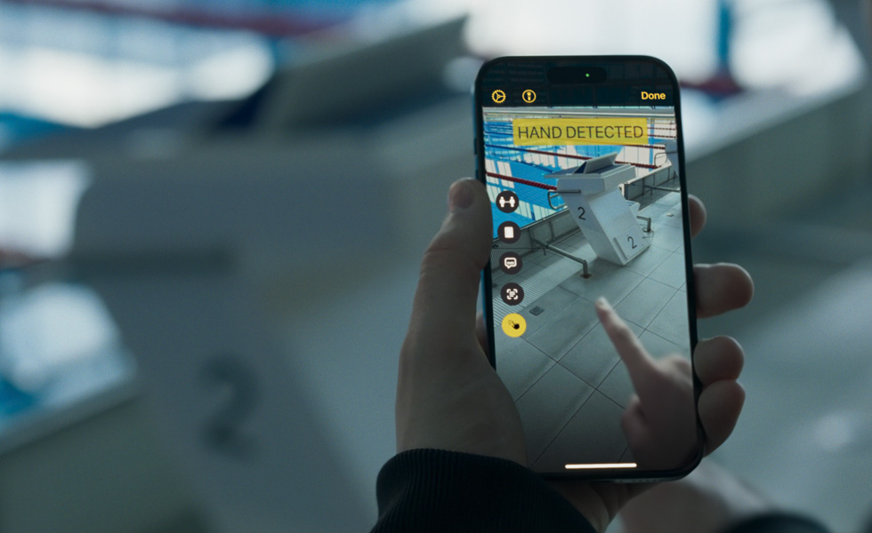 iPhoneを持った手。カメラは水泳のスタート台に向けられている。iPhoneの画面上に指をかざすと、「手が検出されました」という文字が表示される。