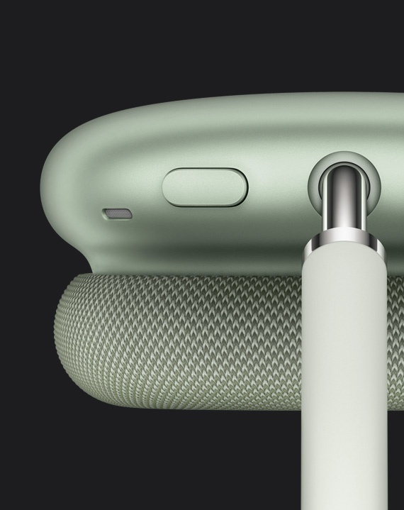 Gros plan sur le bouton de contrôle du bruit sur le dessus de la coque d’écouteur à côté du point de raccordement de l’arceau, sur des AirPods Max en vert.