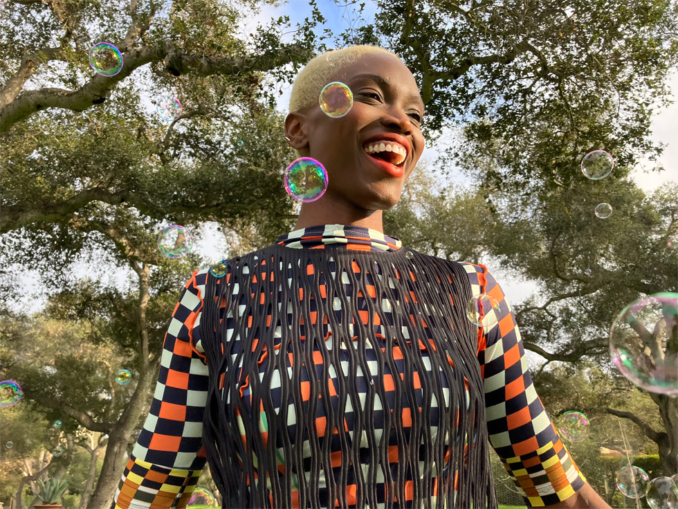 A vibrant photo of a person standing outdoors surrounded by bubbles.