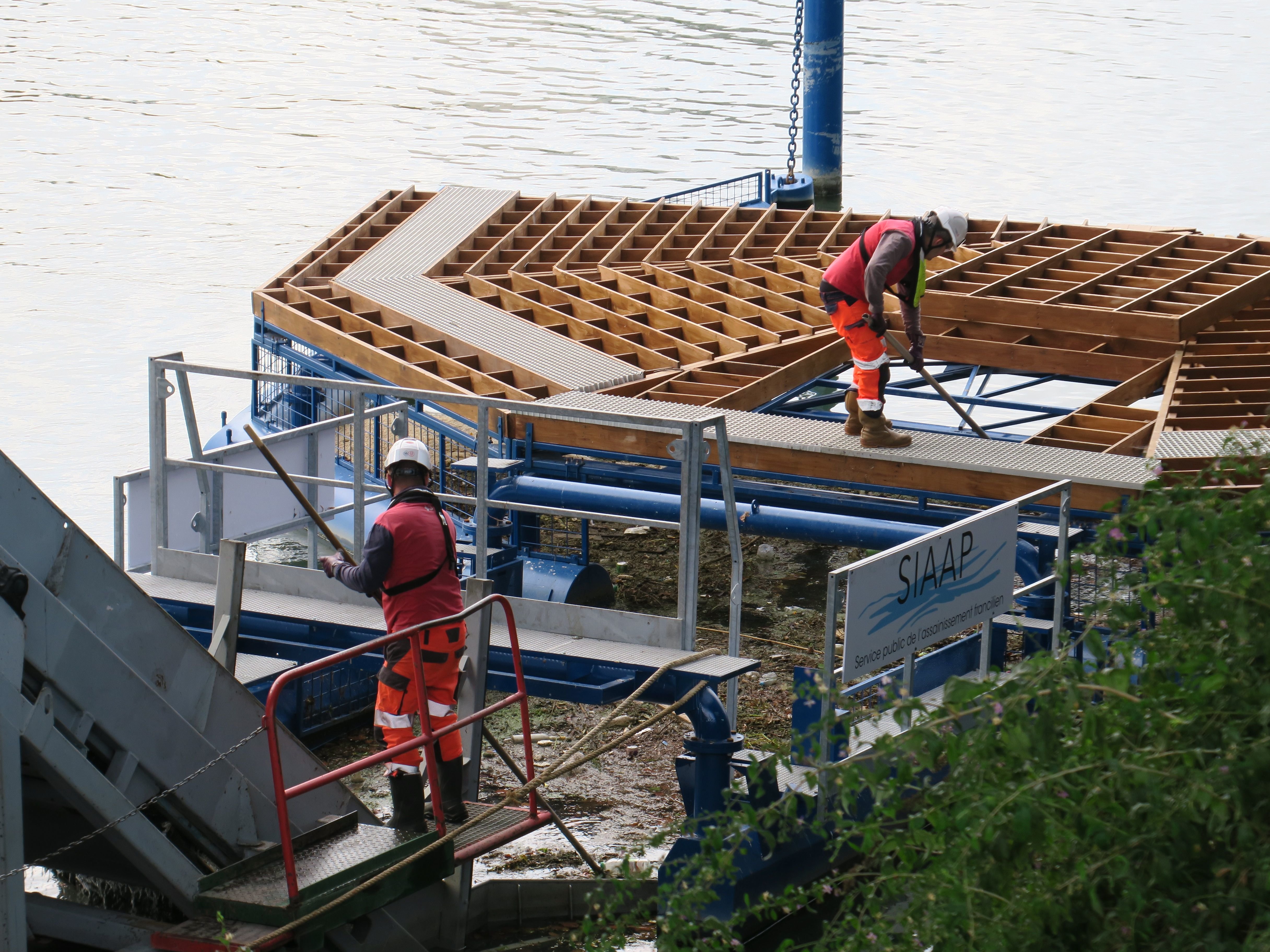 Choisy-le-Roi (Val-de-Marne), le 4 septembre. Sur la Seine, sous le pont de l'A86, ces deux agents viennent une fois par semaine avec une barge équipée d'un convoyeur (à g.) récupérer les déchets collectés par le nouveau barrage flottant du SIAAP. LP/Marine Legrand