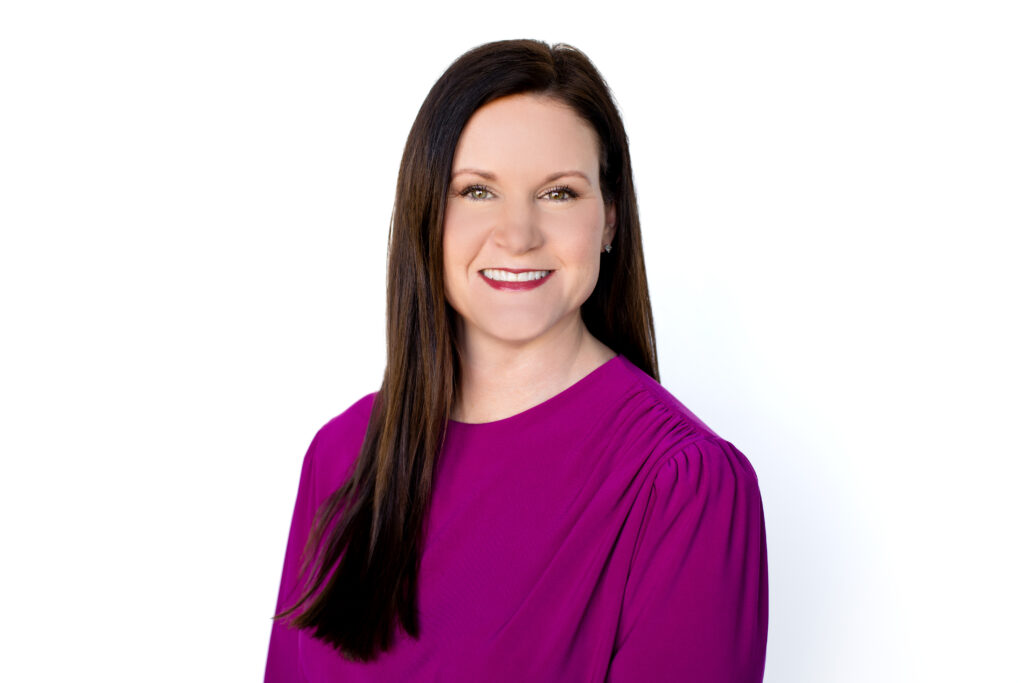 White woman with long dark hair wearing a purple top.