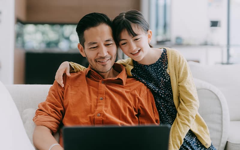 un padre y su hija viendo una laptop