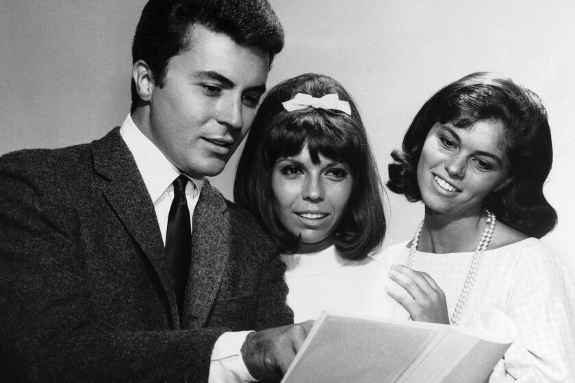 FILE - James Darren — left, one of the stars of the film For Those Who Think Young — chats with Nancy Sinatra, centre, and Claudia Martin about their film debuts, August 13, 1963. (AP Photo, File)