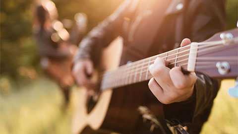 People playing the guitar in the sunlight.