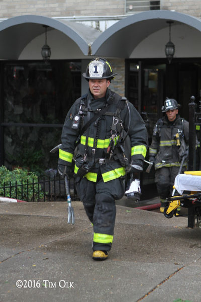 firefighter in PPE with tools after a fire