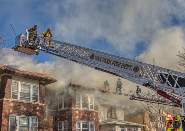 Firefighters on E-ONE tower ladder at fire scene