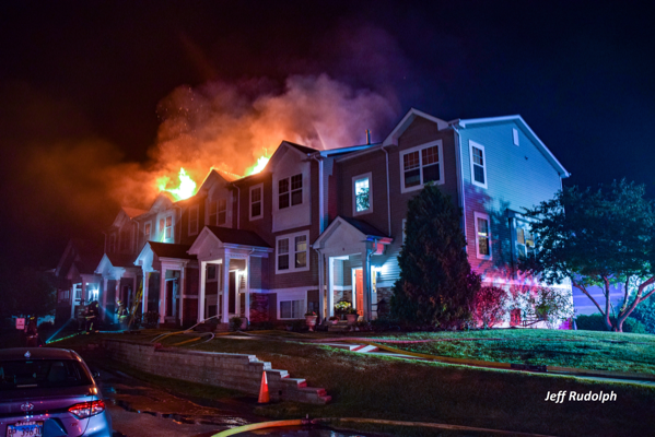 flames through the roof of a townhouse at night