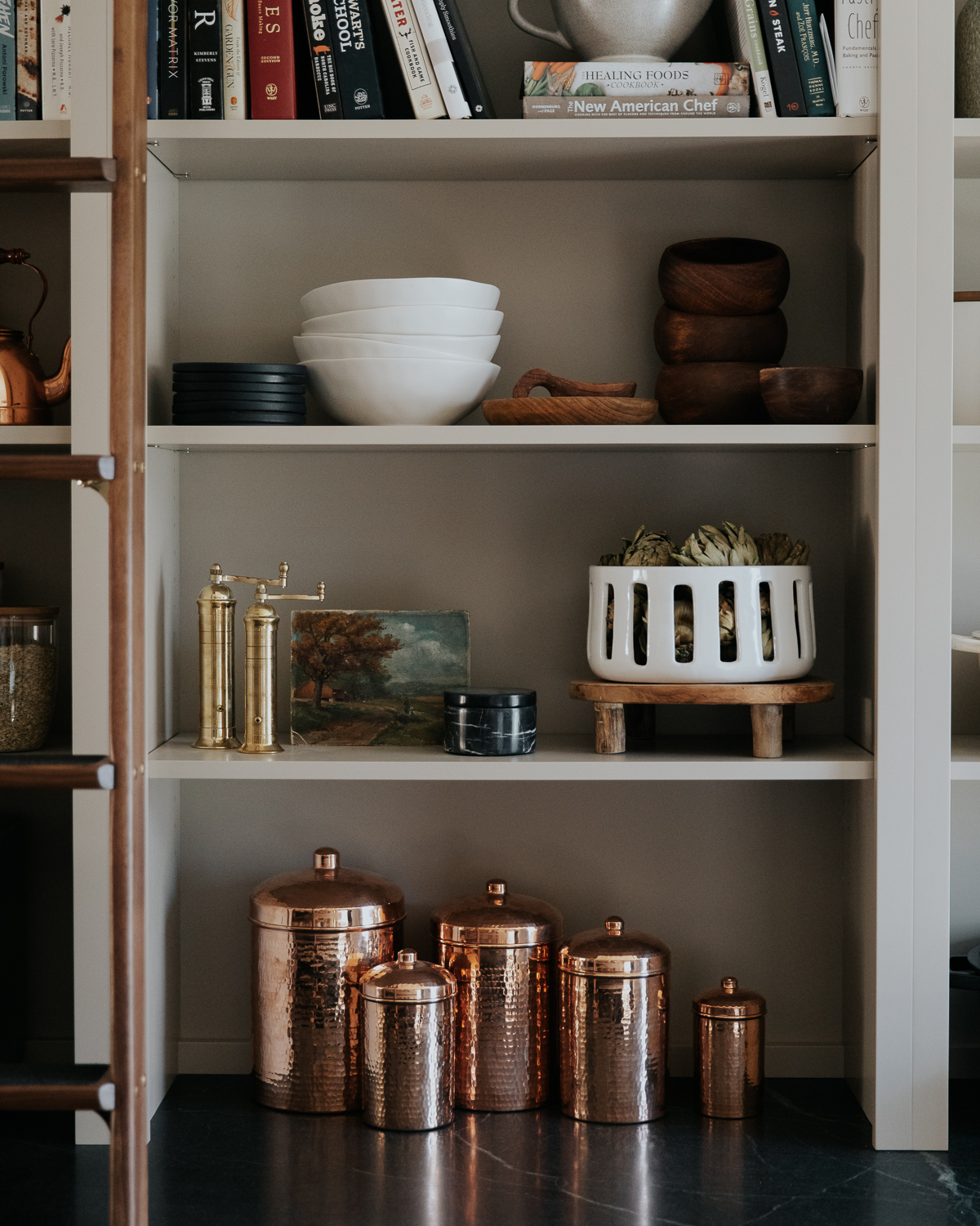 Kitchen shelves with copper canisters, brass pepper and salt grinders, small art and bowls