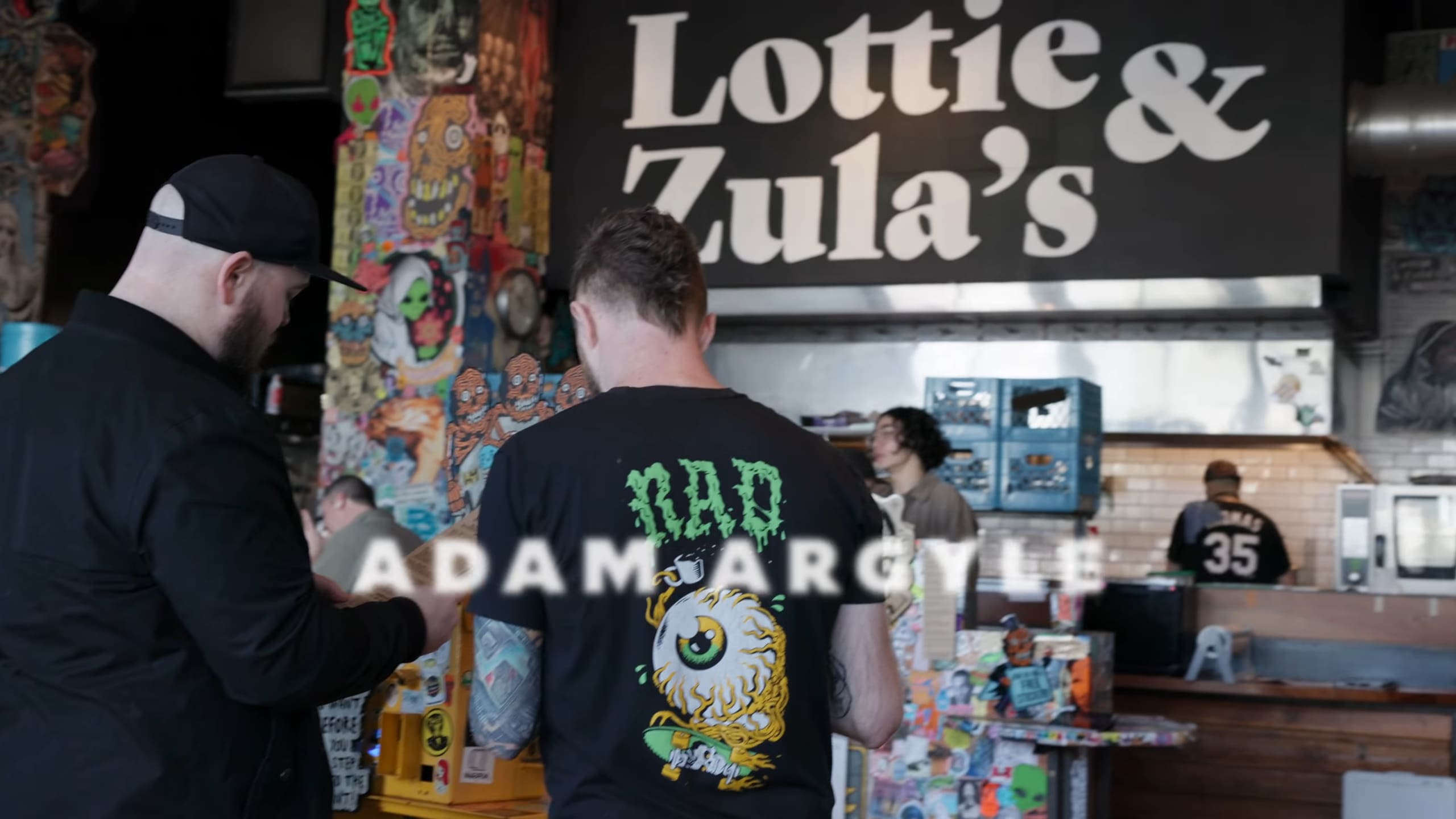 Jason and Adam looking at a food menu in a punky lunch location.