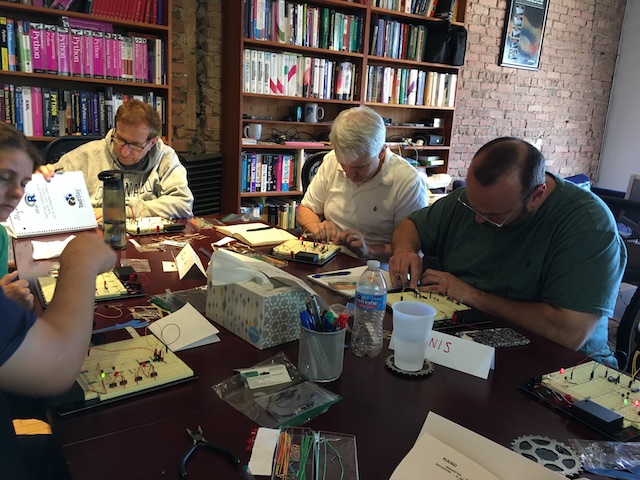 students sitting around a table building circuits on breadboards