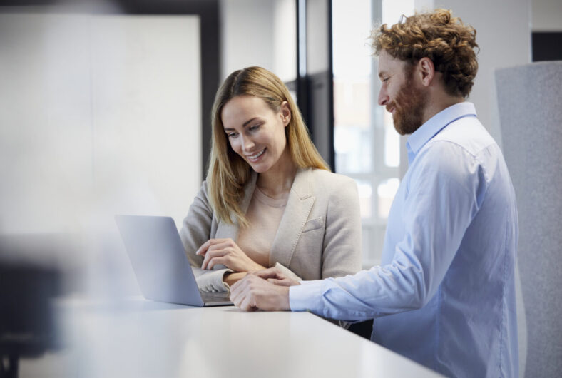 Businessman and businesswoman working together with laptop in office