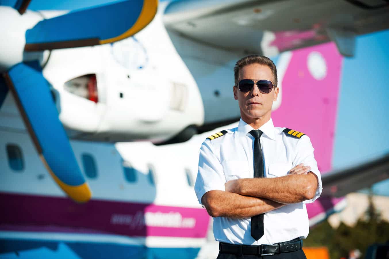 A career pilot stands next to a large propeller driven airliner.