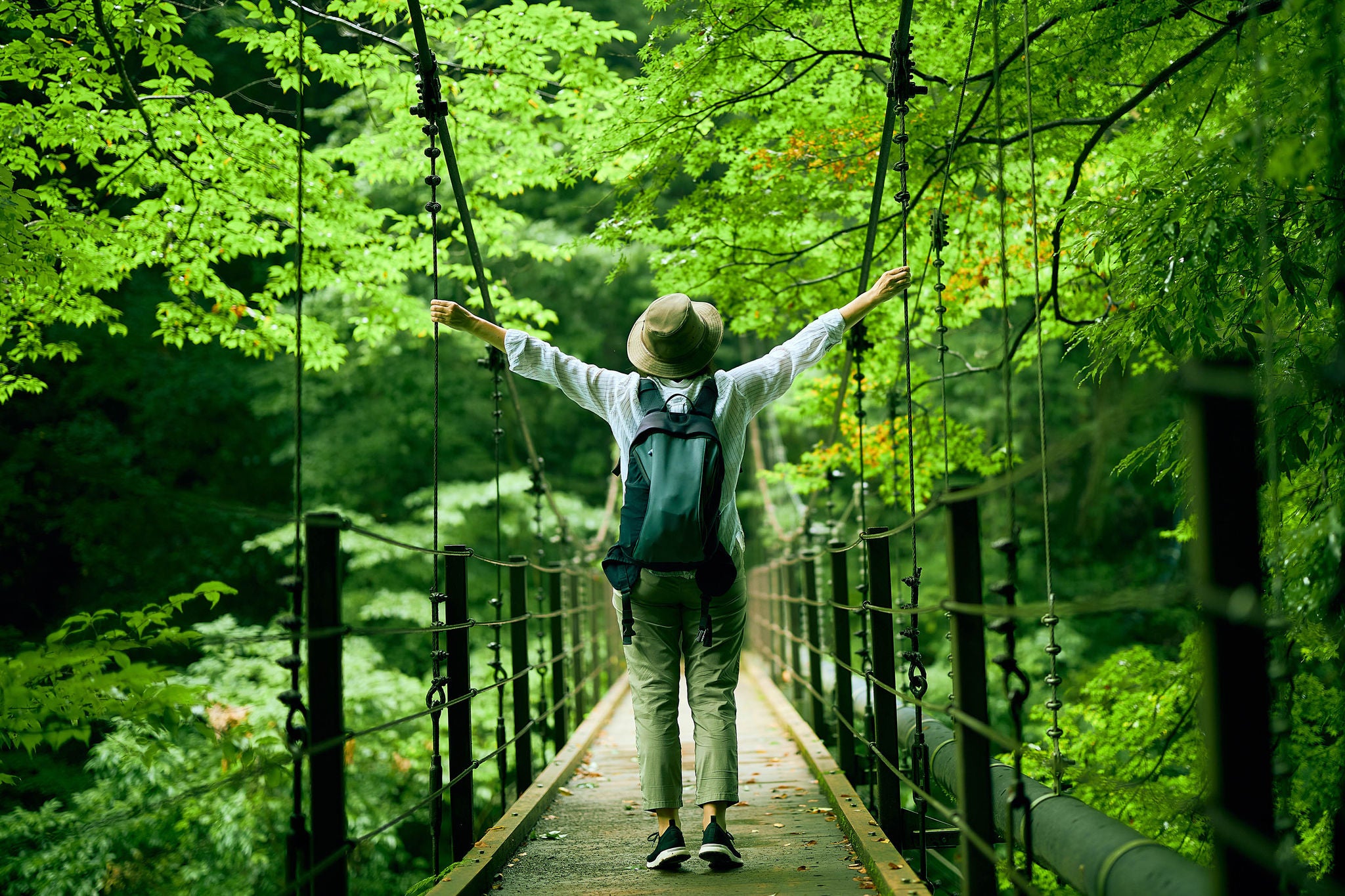 Woman walking alone on suspension bridge in valley in the water source of Tokyo