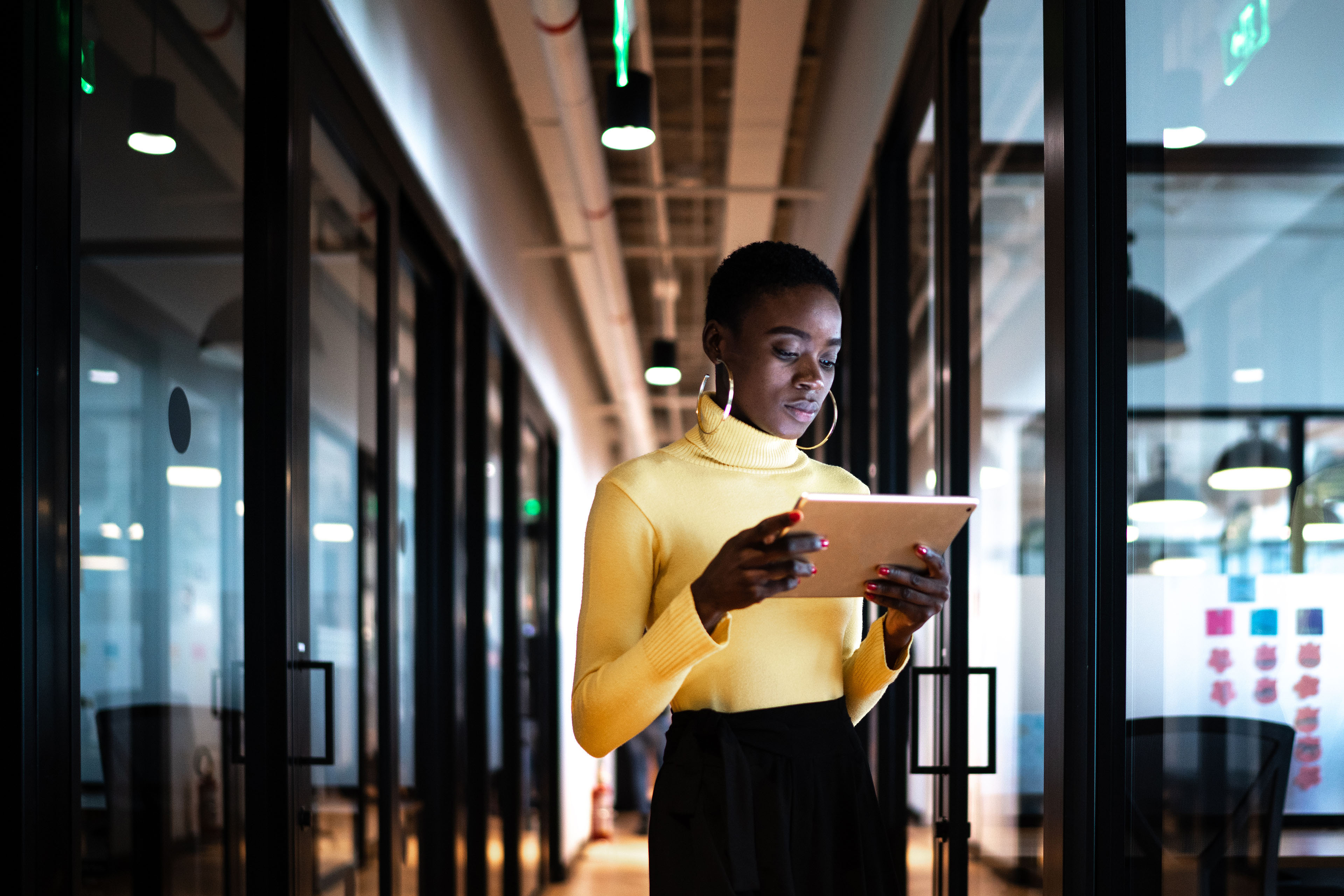 Young businesswoman walking and using digital tablet at corridor office