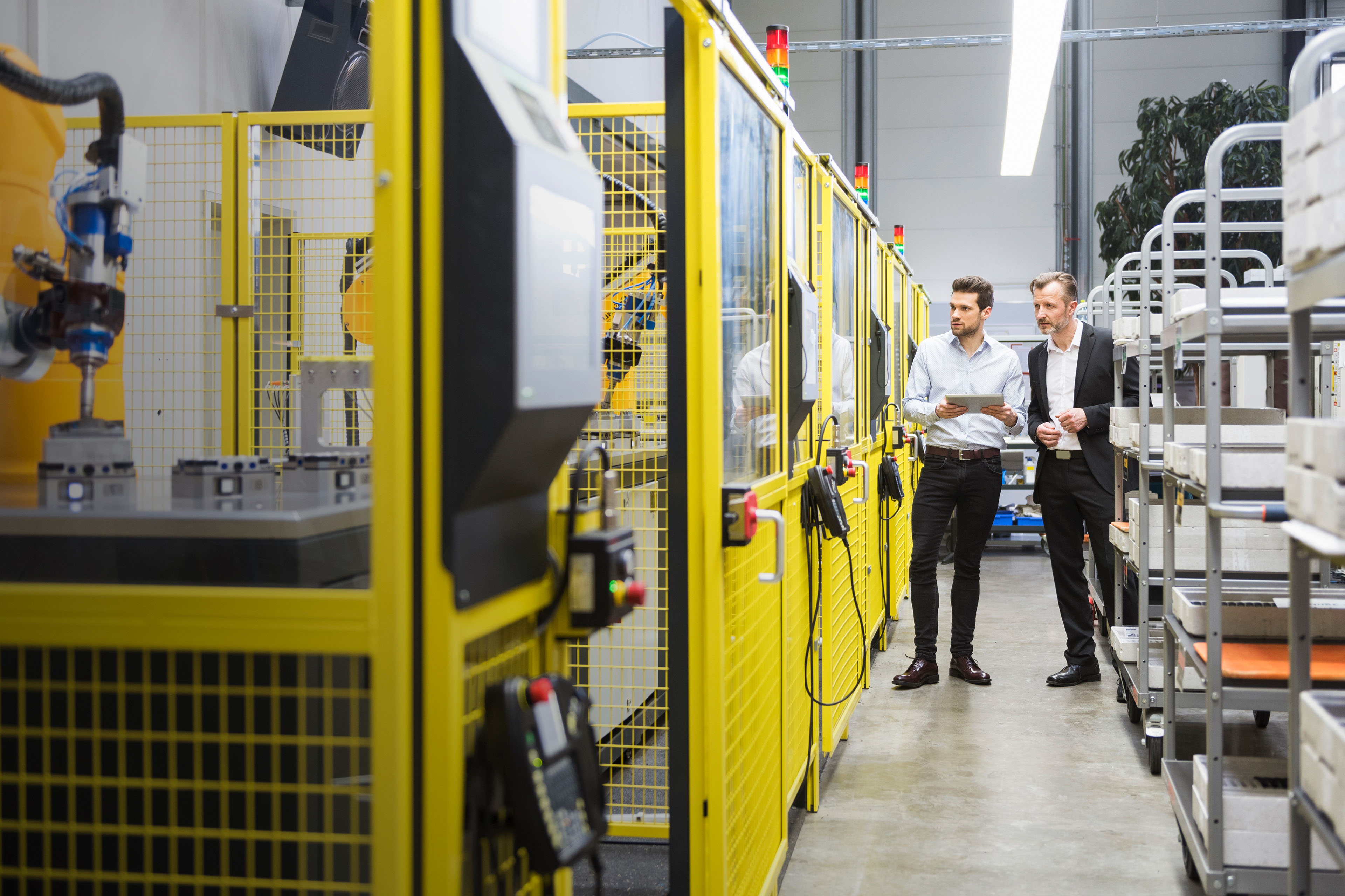 Two businessman observing industrial robots in factory