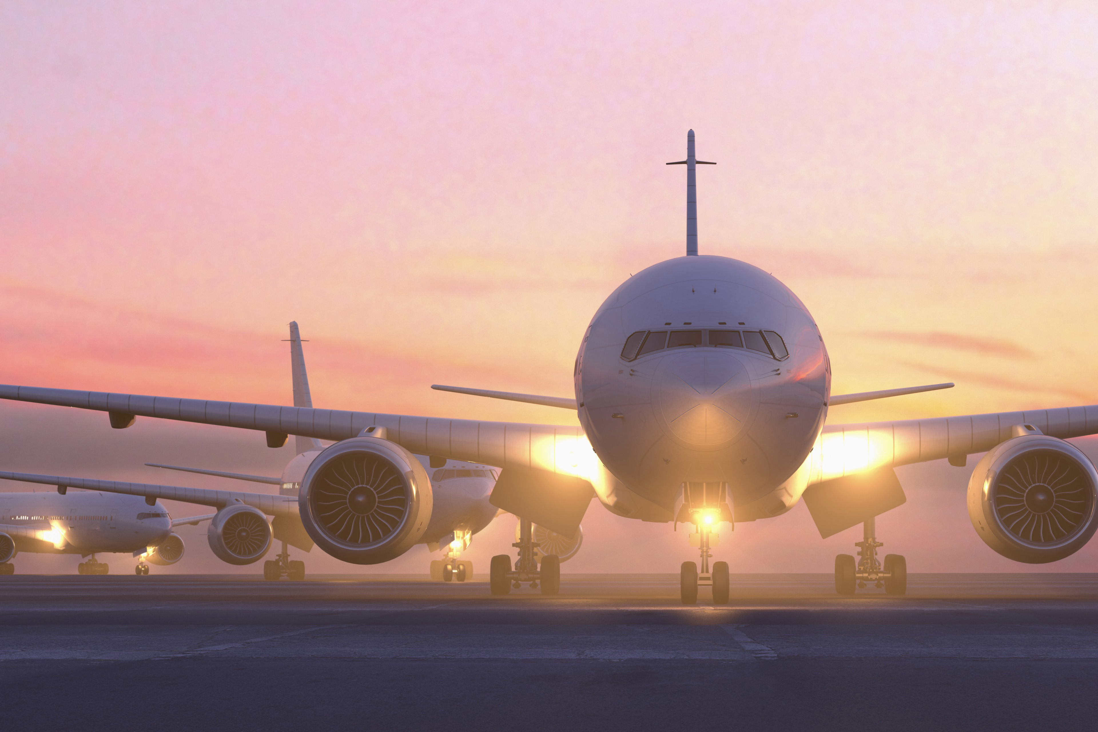 Airplanes taxing on runway at sunset