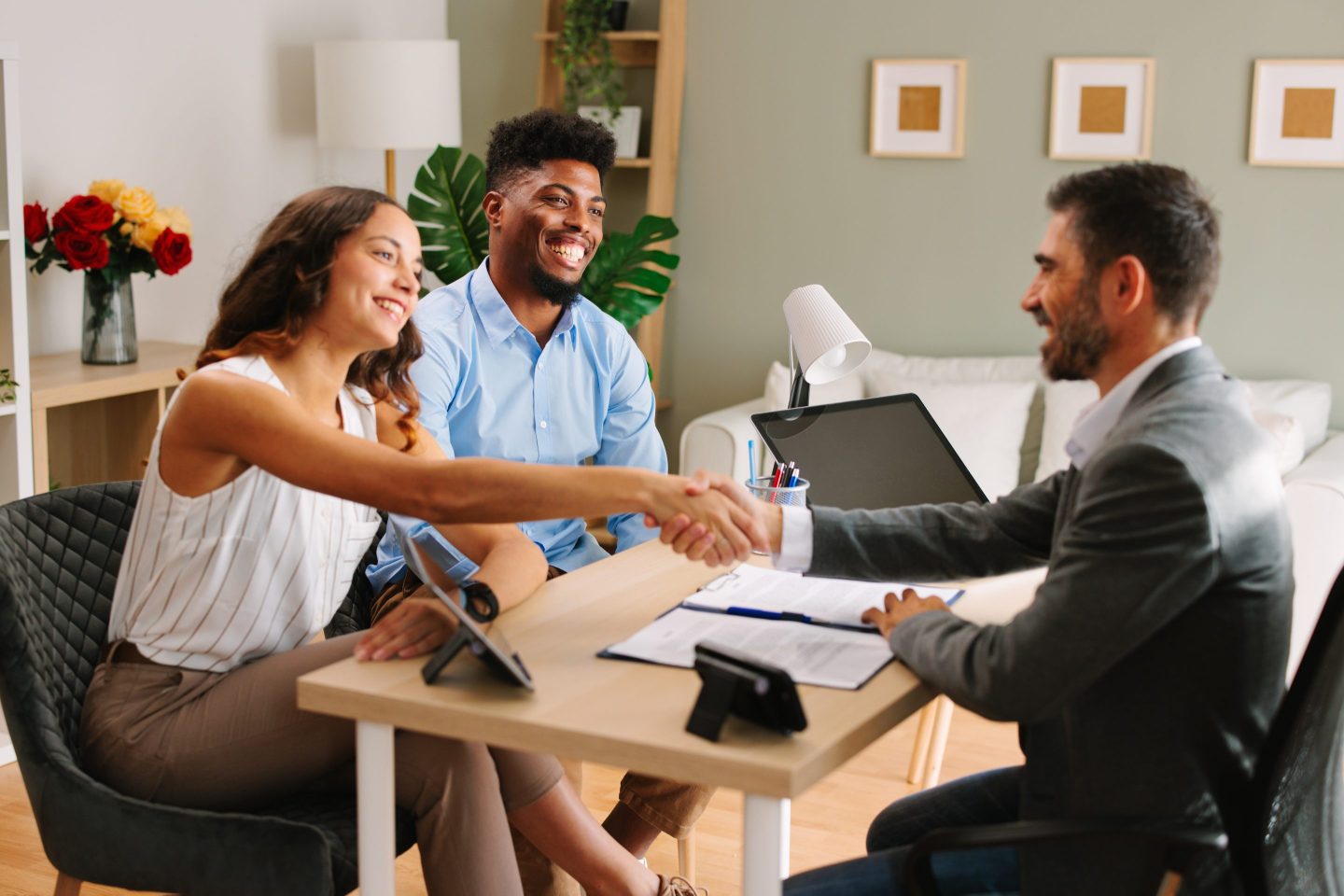 Woman reaches across a table to shake a real estate agent's hand.