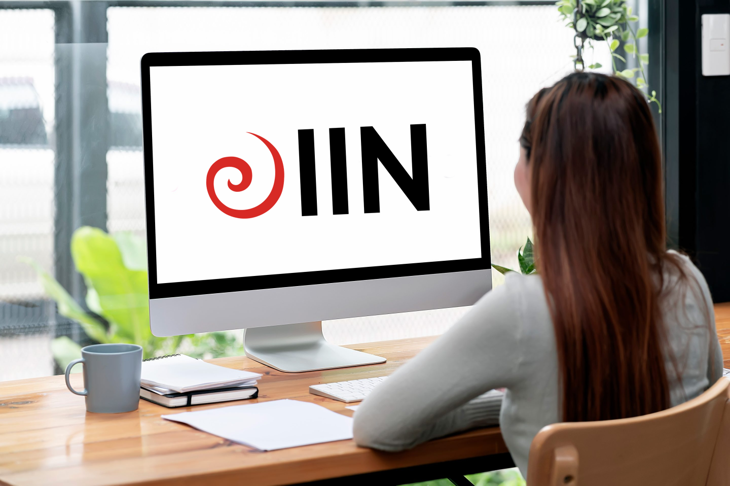 A person working on a computer with the IIN Health Coach logo on the screen.