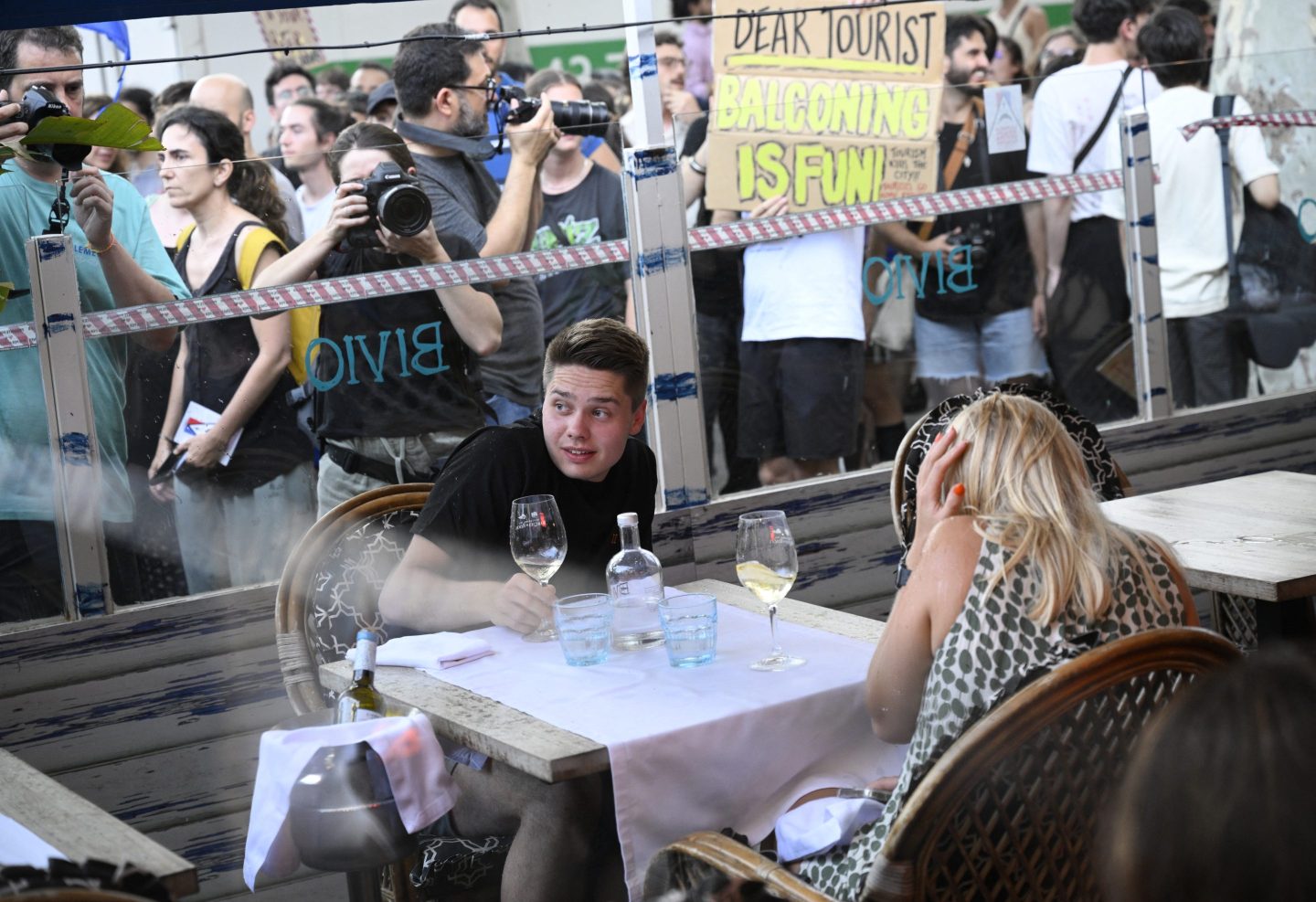 Demonstrators put symbolic cordon on a bar-restaurant window during a protest against mass tourism on Barcelona's Las Ramblas alley, on July 6, 2024.