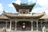 This photo depicts the Temple of Arkhats, showcasing traditional East Asian architecture with its ornate design. The building features tiered, tiled roofs with upturned eaves and decorative elements. The entrance is framed by a central doorway, flanked by pillars, and topped with a richly decorated balcony and green roof tiles.