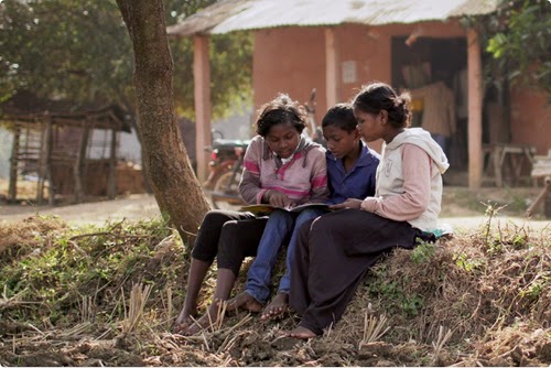 Três jovens negros lendo em uma área rural.