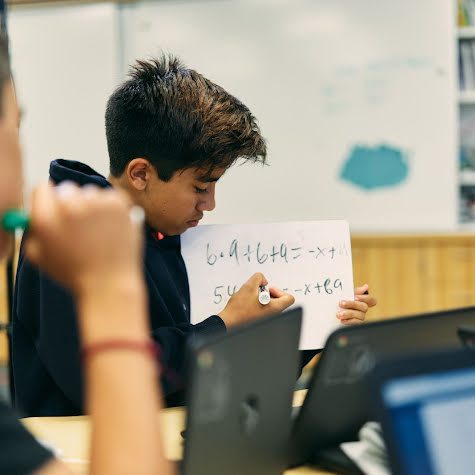 Two boys in a classroom working on math problems.