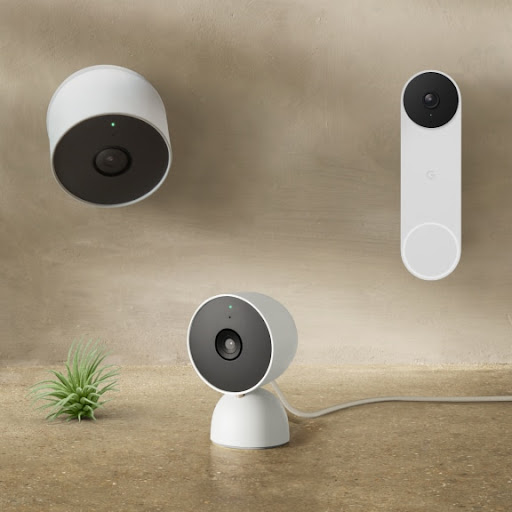 An array of Nest devices, including doorbells, speakers, displays, cameras and more are all laid out on a table and installed on a wall.