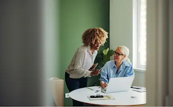 Due donne sono riunite davanti a un laptop per parlare di lavoro.