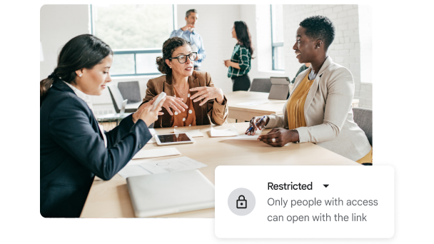 Una reunión entre tres personas con un gráfico que indica “Restricted” (“Restringido”). 