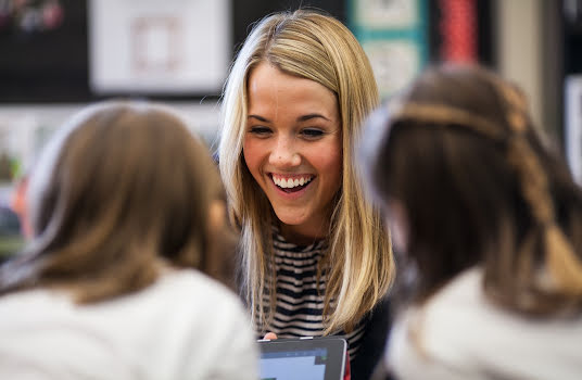 Three young women smiling and talking.