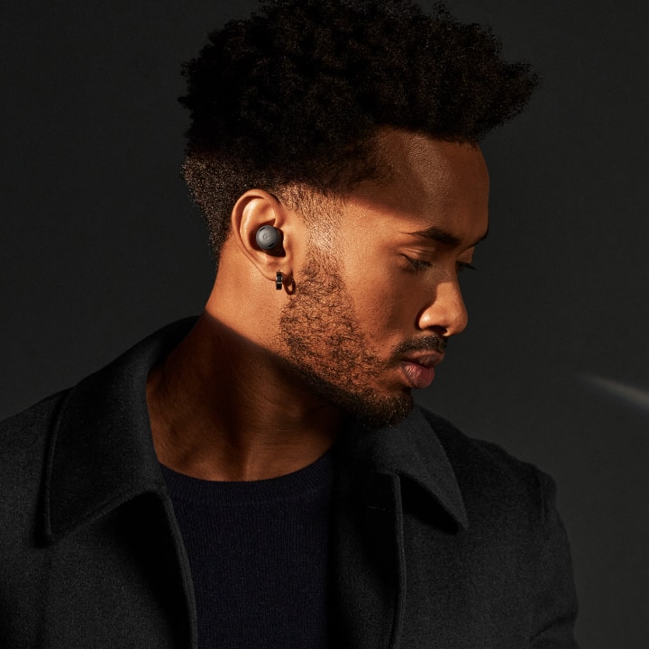 A person looks down while a ray of light illuminates the pair of Charcoal Pixel Buds Pro in their ears