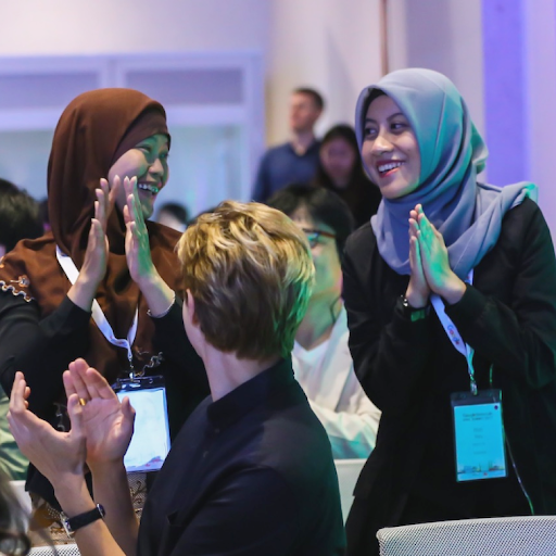 Two girls wearing hijabs clap and smile at each other