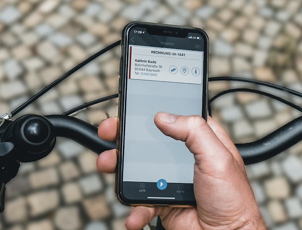 Mensajero en bicicleta mirando una dirección en su teléfono