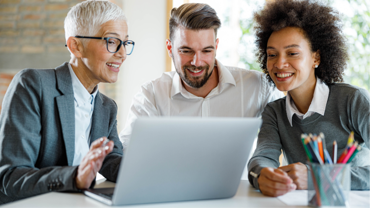 Trois personnes discutent d'une présentation de vente sur un ordinateur portable.