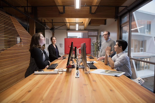 Administradores de TI que hablan en una mesa con computadoras en el medio