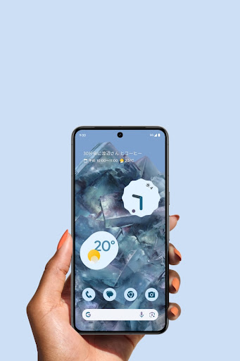 Bay カラーの Google Pixel 8 Pro を持っている手。スマートフォンのホーム画面が新しいディスプレイとともに明るく輝いている。