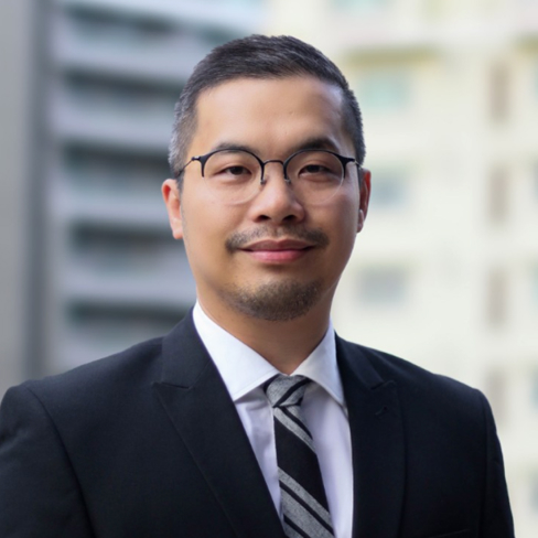 Man in glasses and a business suit looks towards camera