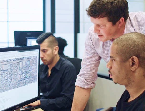 Dos hombres mirando un mapa satelital en una computadora