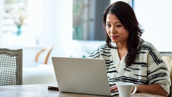 Seorang perempuan sedang bekerja menggunakan laptop