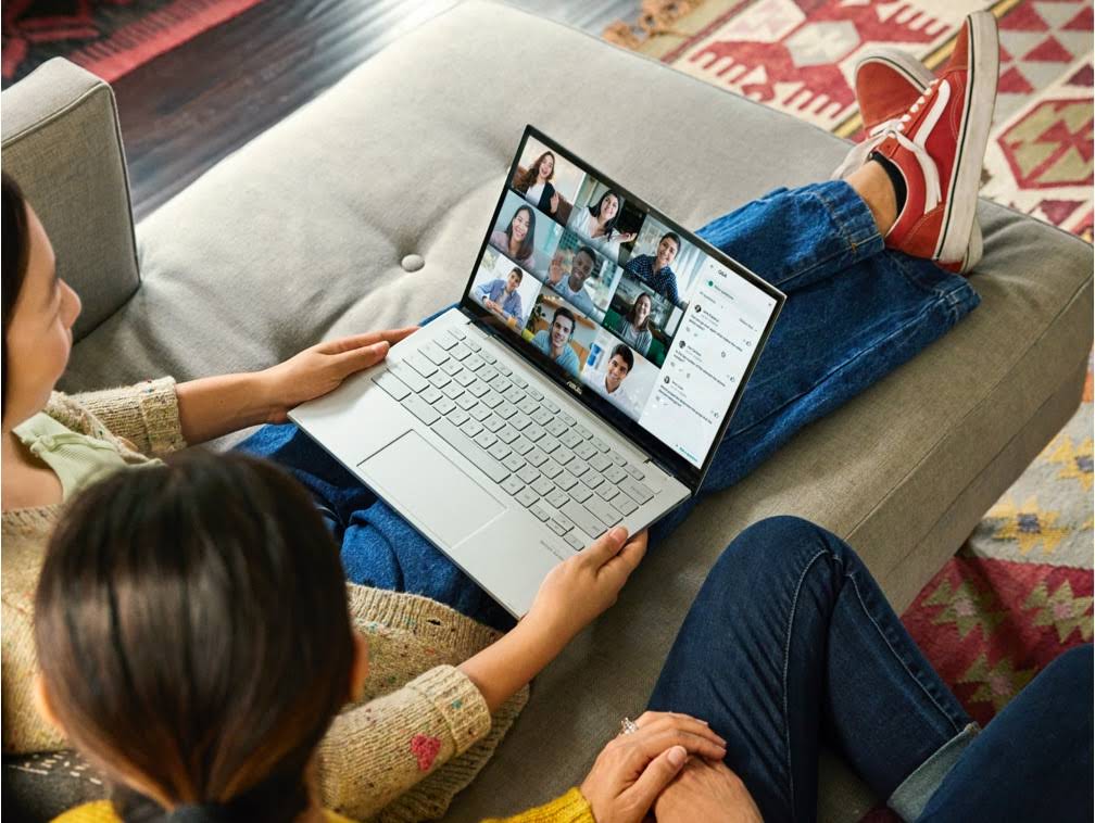 一緒にソファに座って Google Meet の会議に参加する 2 人の女性