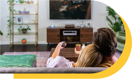 A young couple is comfortably seated on a couch and enjoying a movie.