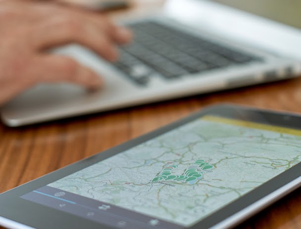 Una persona trabajando en un portátil con un tablet que muestra un mapa