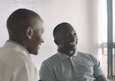 Founder, Gerald Otim, smiles at a table with colleagues.