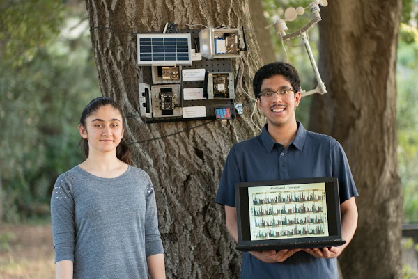 学生の Aditya Shah と Sanjana Shah が自ら開発した AI 搭載の Smart Wildfire Sensor の前に立っている。