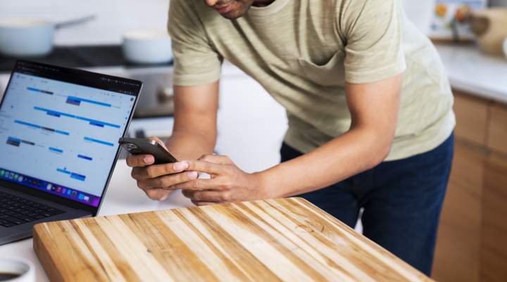 A young man plays games on his phone in the kitchen