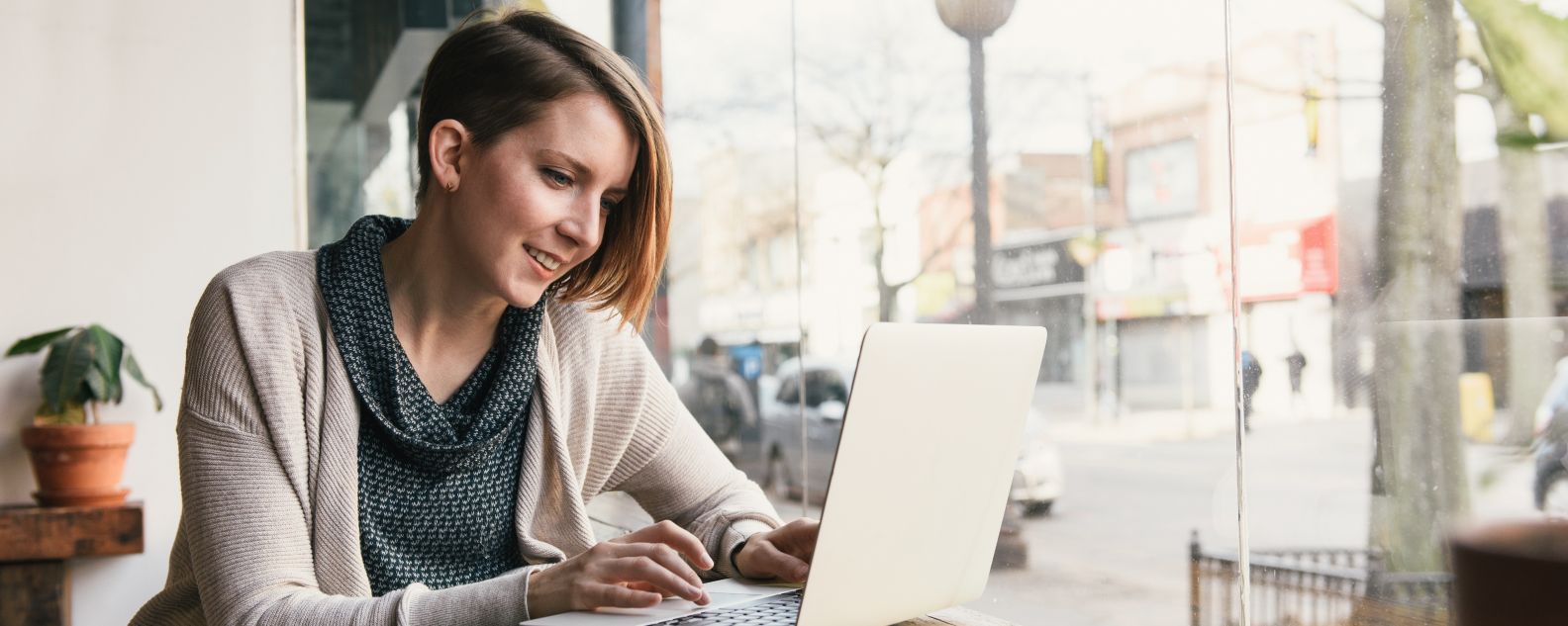 Personne souriante assise dans un bureau en train de travailler sur un ordinateur portable