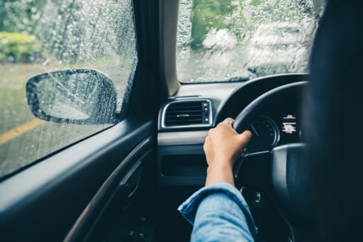 woman driving car on busy road in rain