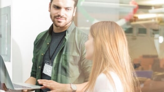 Two IT professionals looking at a laptop computer.